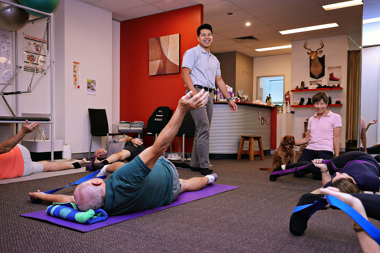 Group physiotherapy session with instructor guiding stretching exercises