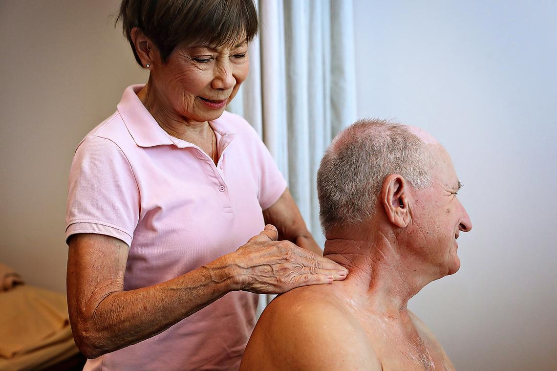 Physiotherapist giving a neck and shoulder massage to an elderly man